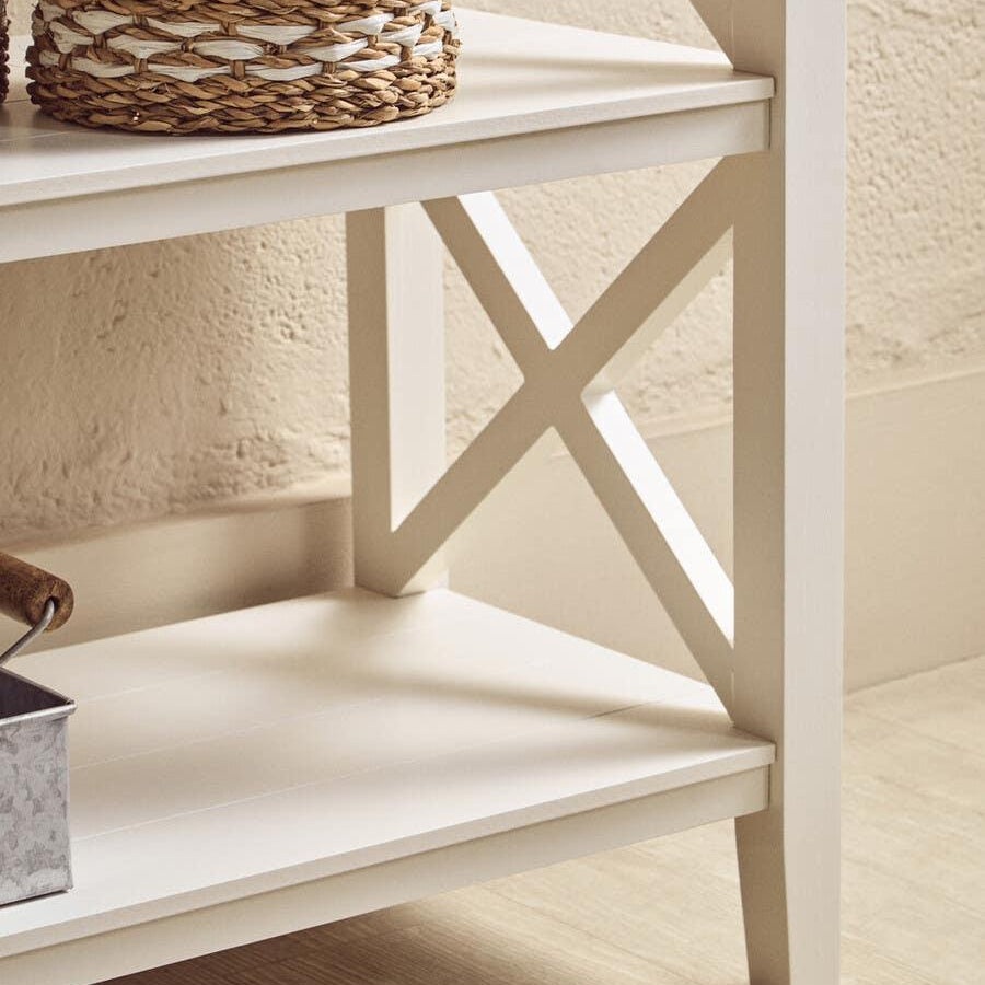 White wooden shelving unit with X-frame detail and woven storage basket on shelf
