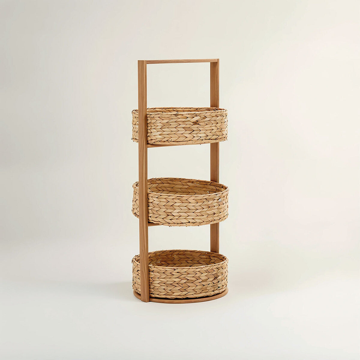 Three-tier storage caddy made from water hyacinth, featuring a natural woven texture and a sturdy handle on top for easy carrying. Each tier consists of round, open baskets, providing a stylish and functional storage solution. The caddy is set against a light, neutral background