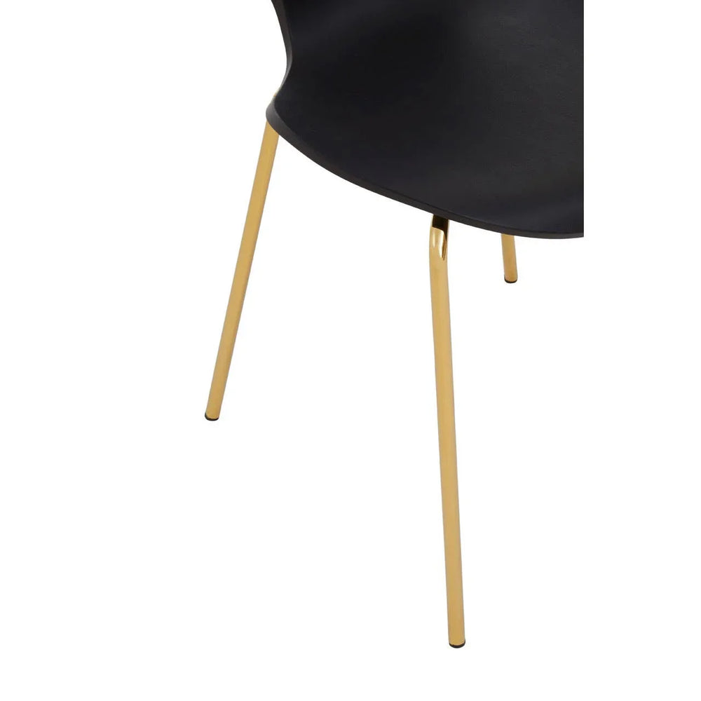 Black dining chair with gold metal legs close-up