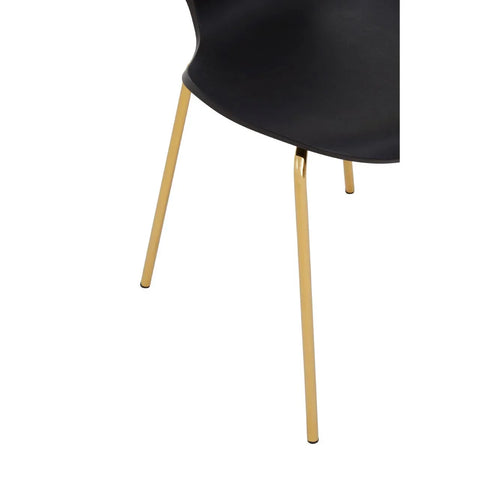 Black dining chair with gold metal legs close-up