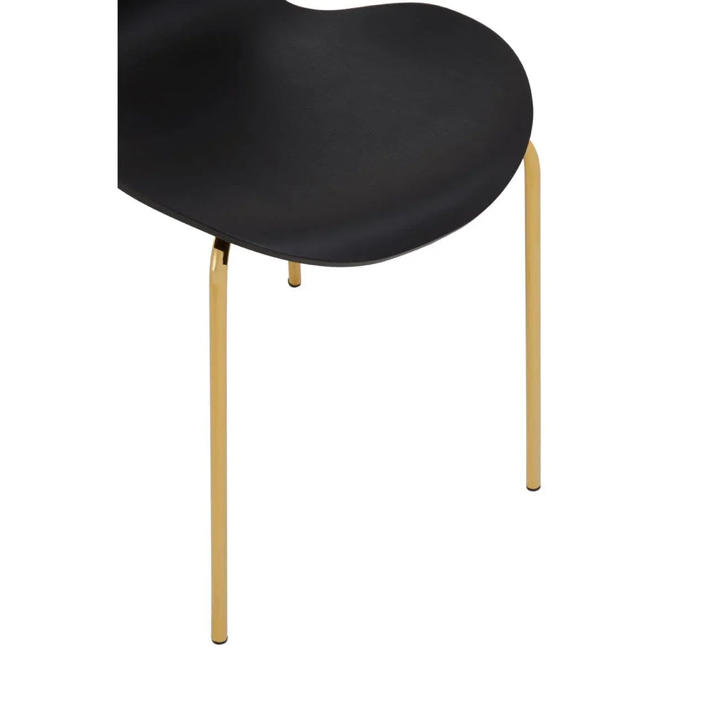 Black dining chair with curved seat and slim gold metal legs, close-up view