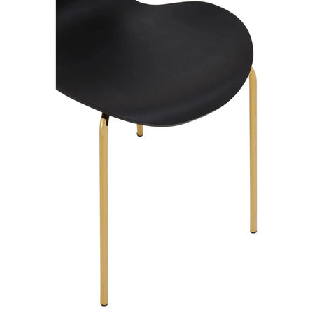 Black dining chair with curved seat and slim gold metal legs, close-up view