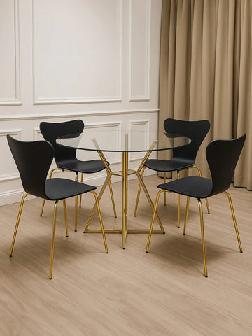 Glass dining table with gold metal legs and four black chairs in modern dining room