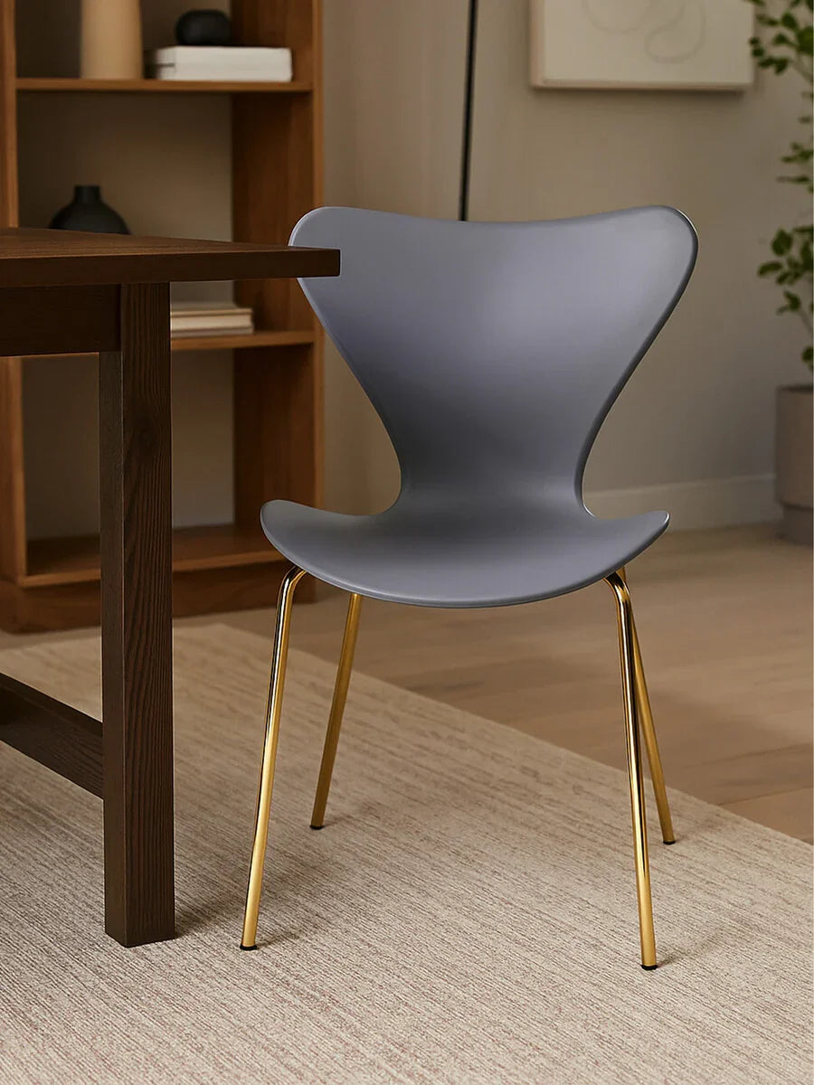 Grey dining chair with gold metal legs beside dark wood table on beige rug