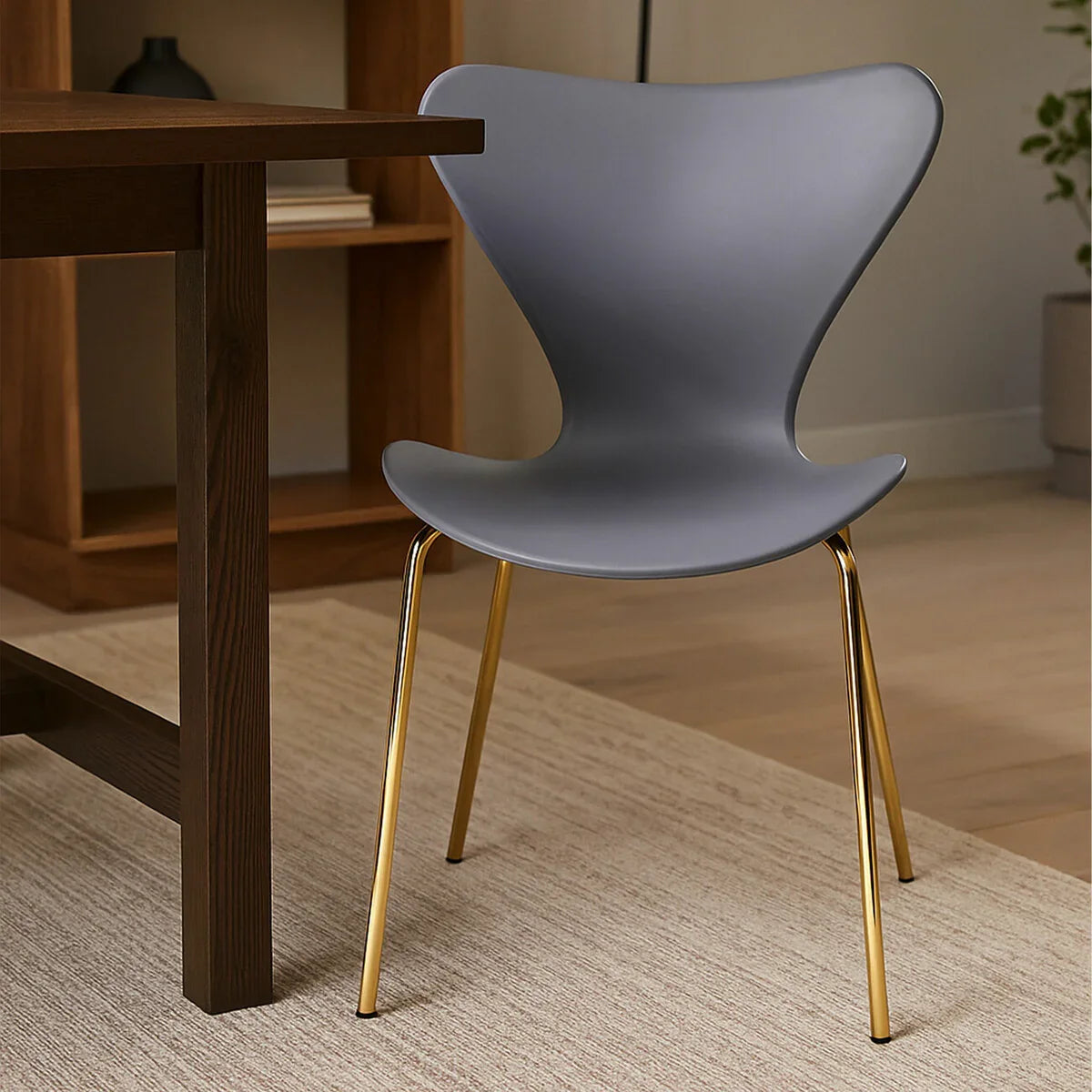 Grey dining chair with gold legs next to dark wood table on beige rug