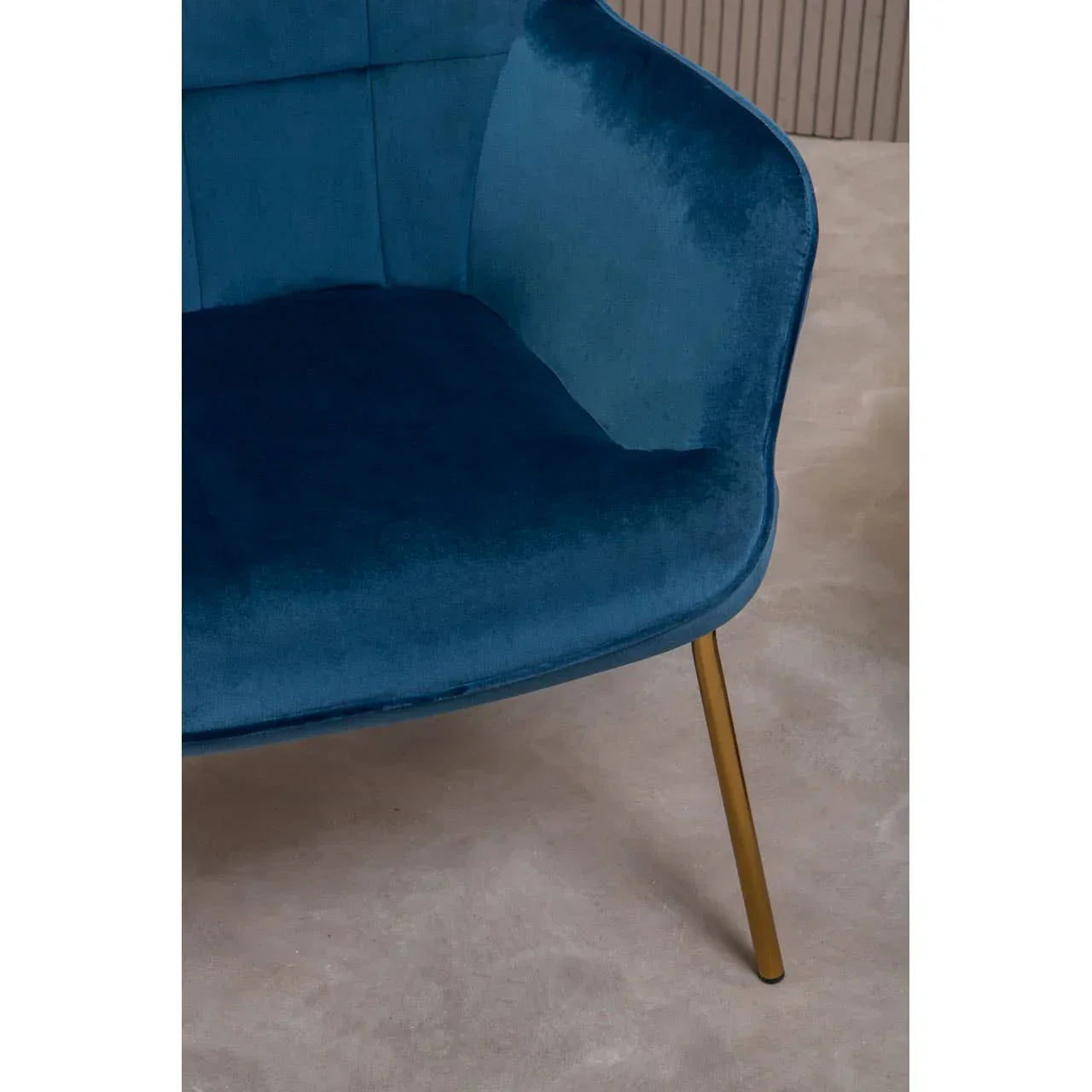 Blue velvet accent chair with gold metal leg on light carpet