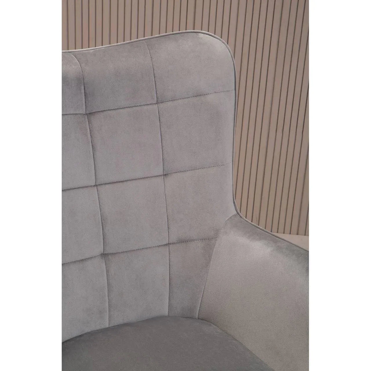 Grey velvet accent chair with quilted backrest and curved armrest in modern setting