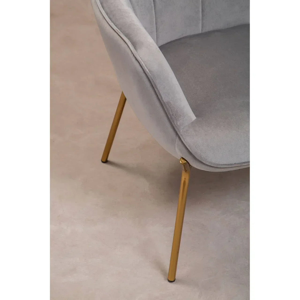 Grey velvet accent chair with gold metal legs, close view of seat and base