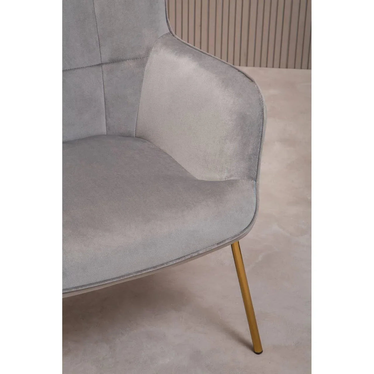 Close-up of grey fabric armchair with gold metal leg on neutral floor