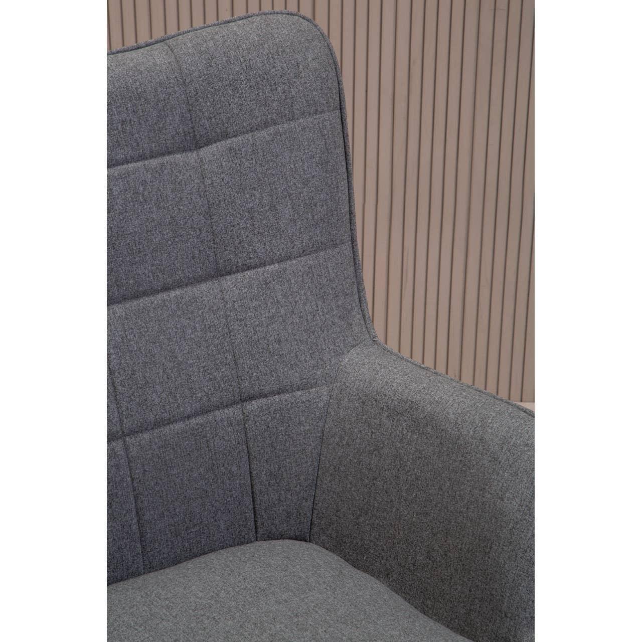 Close up of grey fabric armchair with high back and padded seat against slatted wall