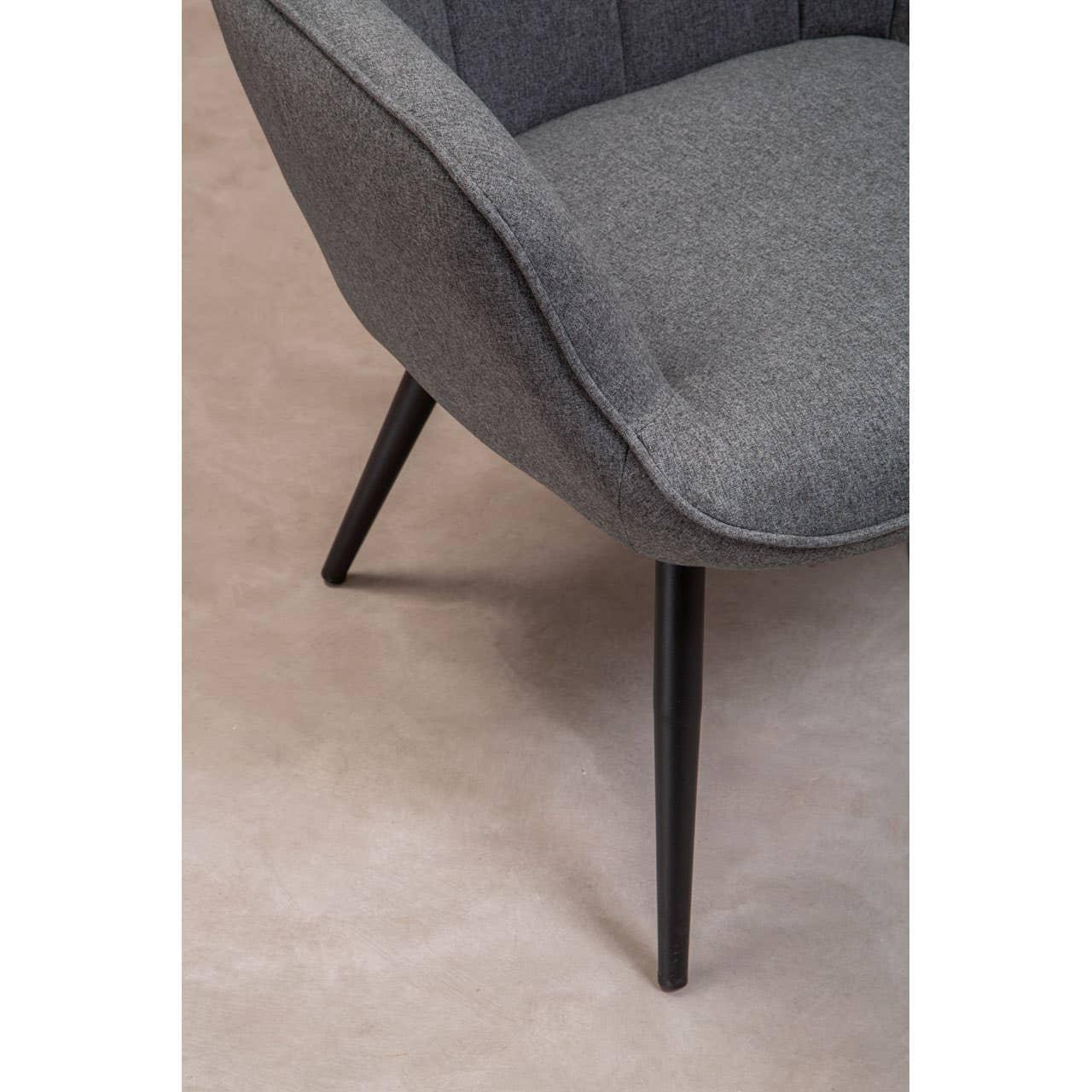 Close-up of grey fabric accent chair with angled black legs on beige floor
