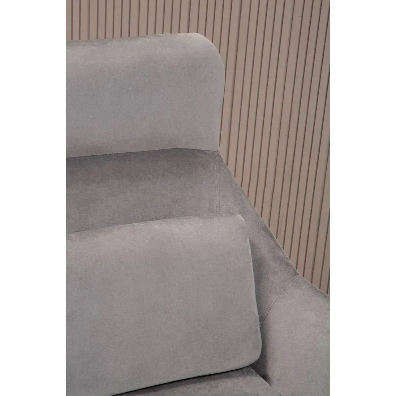 Close view of grey fabric armchair with padded backrest and cushion, modern textured wall