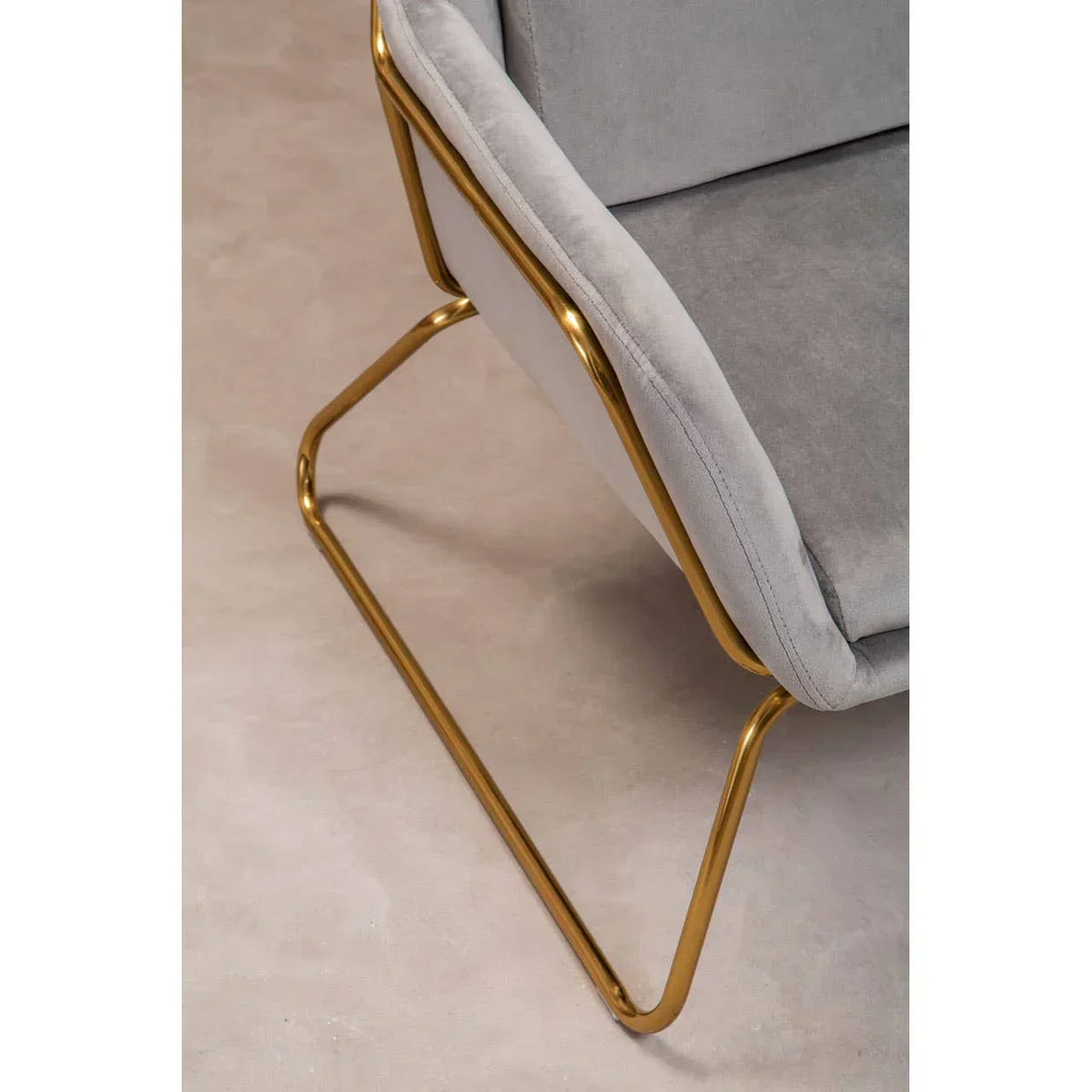 Grey velvet chair with gold metal frame, angled view of seat and leg detail