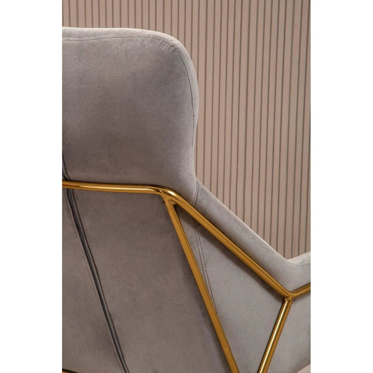 Close-up of grey velvet chair with gold metal frame against a vertical slat wall