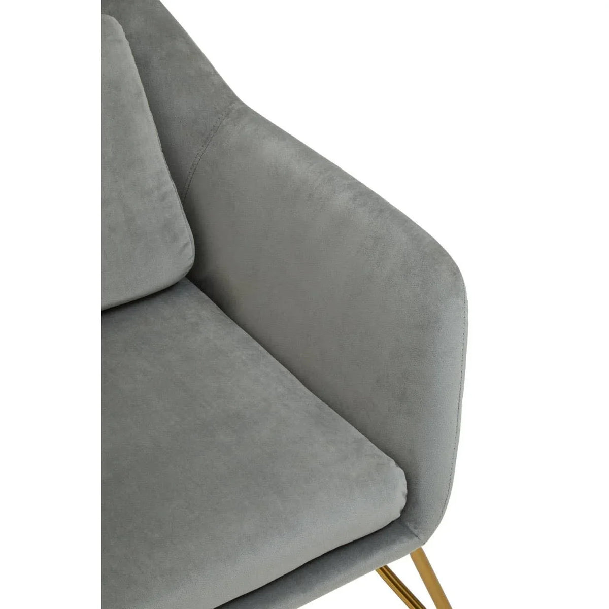 Close-up of grey velvet sofa arm with gold metal leg and plush cushion