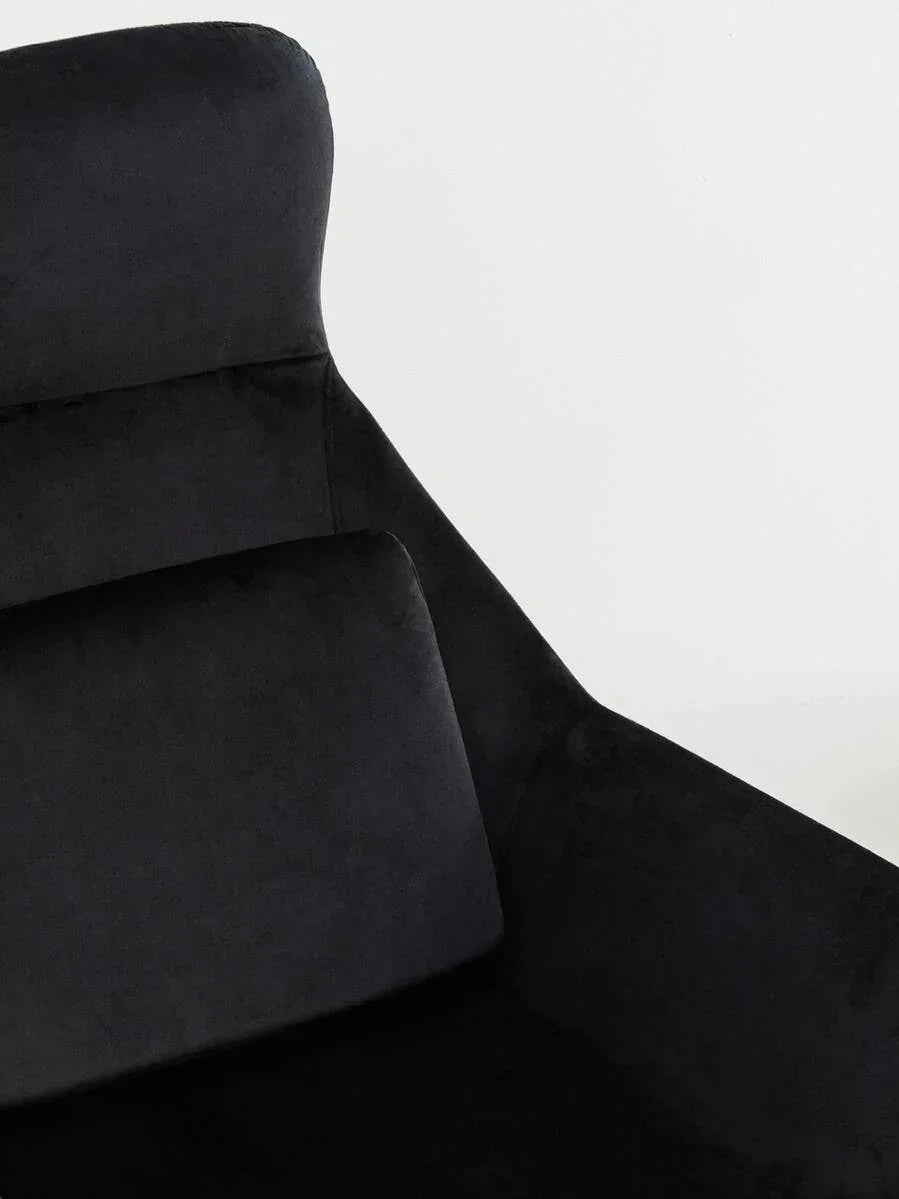 Black velvet armchair with angled backrest and plush cushion, close-up view