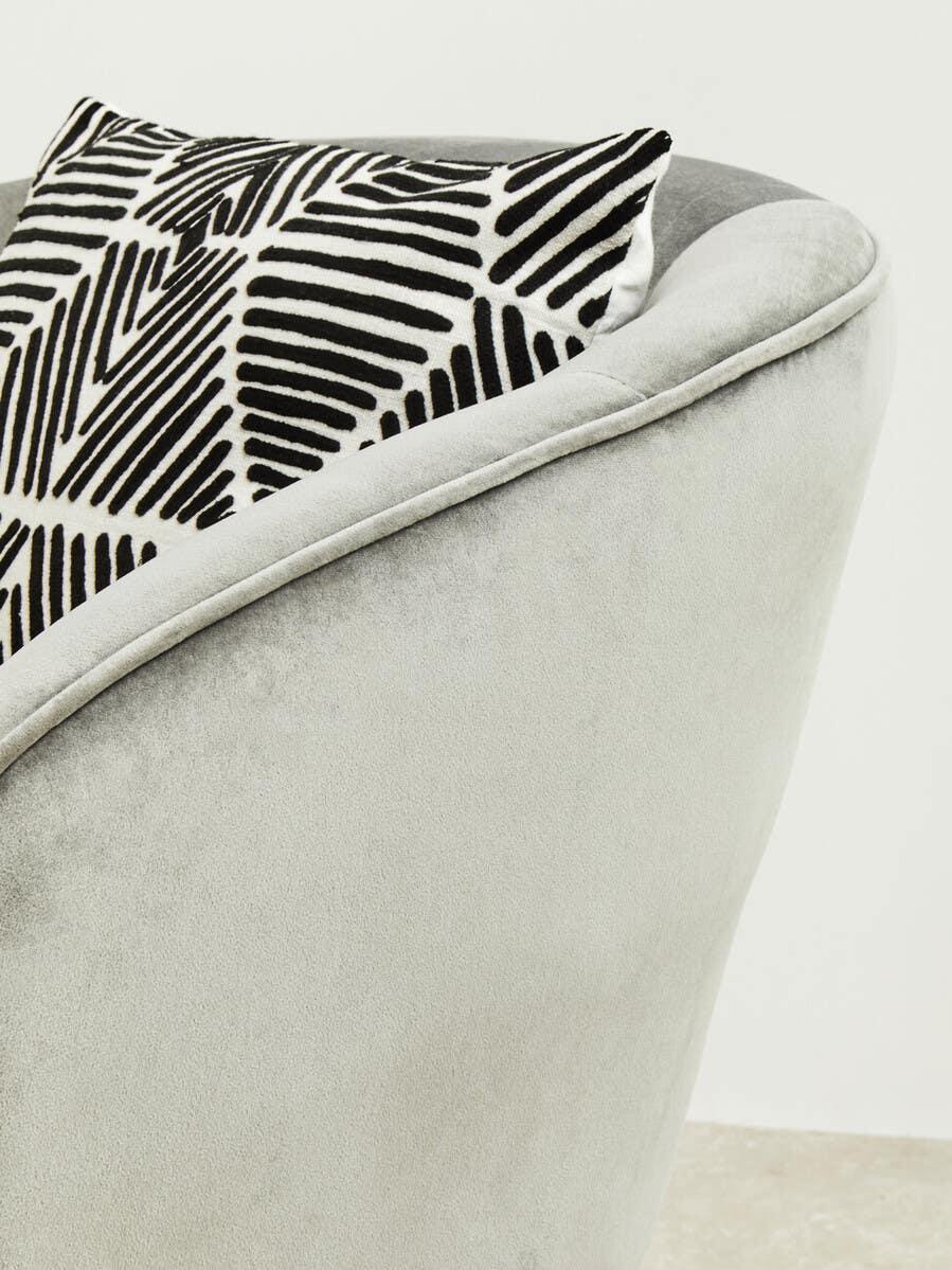 Light grey velvet armchair with black and white geometric cushion