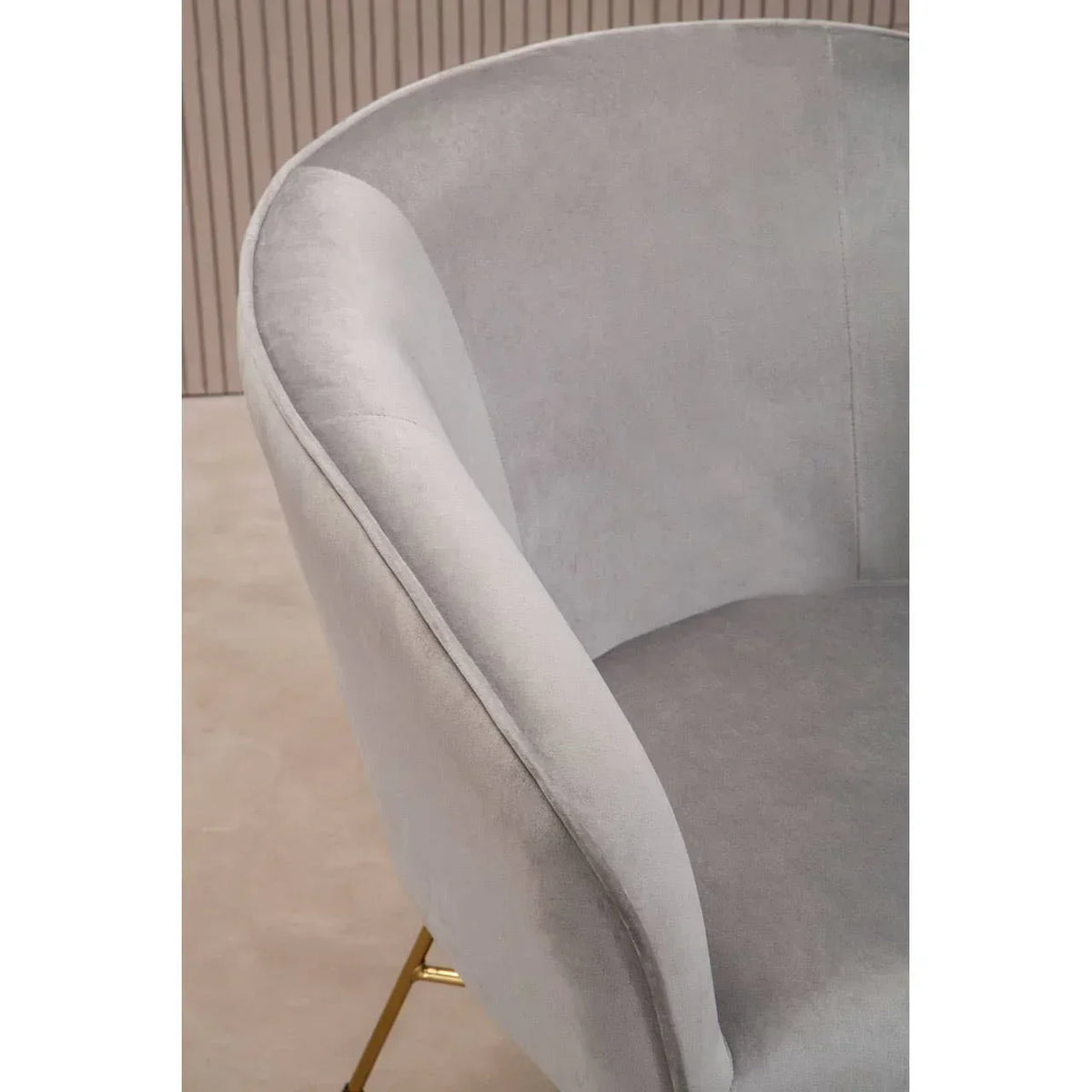 Light grey velvet accent chair with curved back and gold metal legs, closeup side view