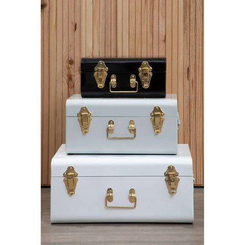 Set of three metal storage trunks with gold latches, stacked against wooden wall