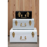 Set of three metal storage trunks with gold latches, stacked against wooden wall