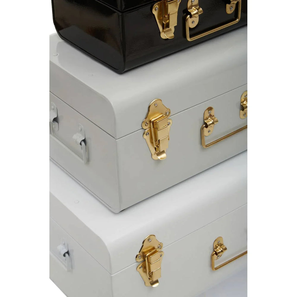 Stacked metal storage trunks with gold latches in black and white finish