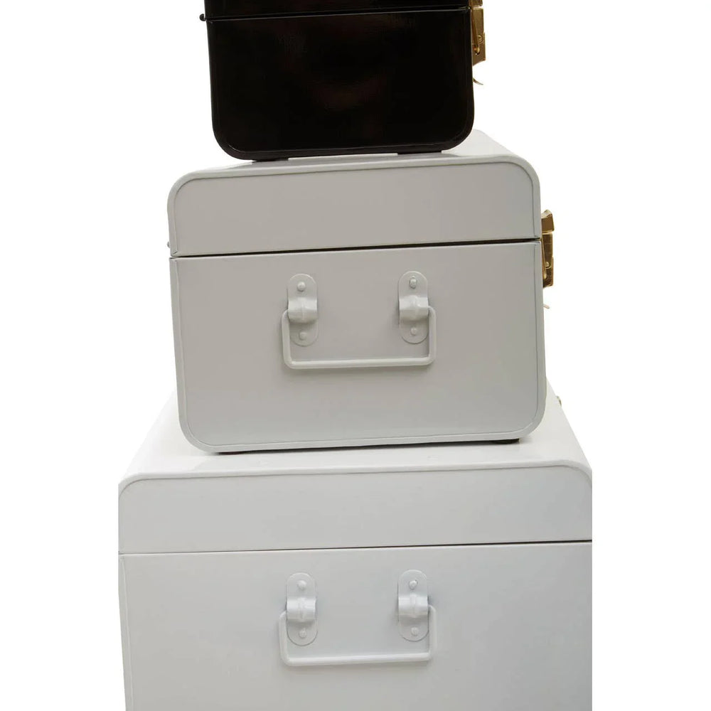 Stacked metal storage trunks in black and white with side handles and gold clasps