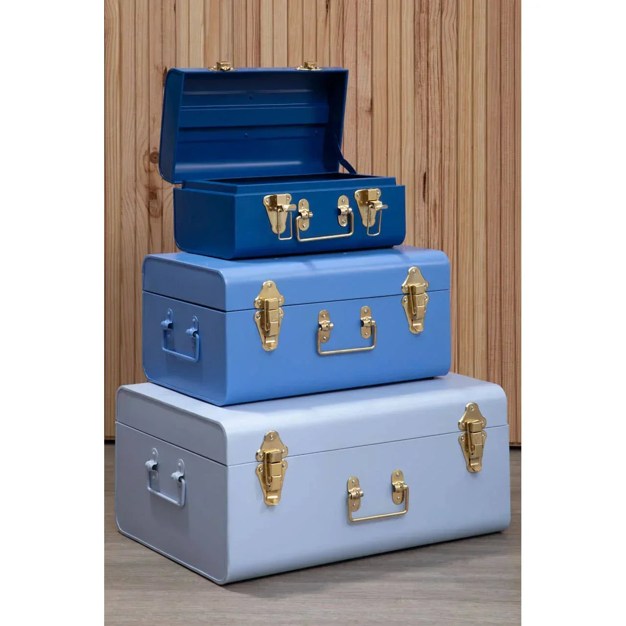 Stack of three metal storage trunks in blue tones with gold handles and latches