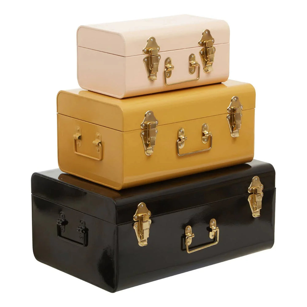 Set of three metal storage trunks in cream, mustard, and black with gold clasps and handles