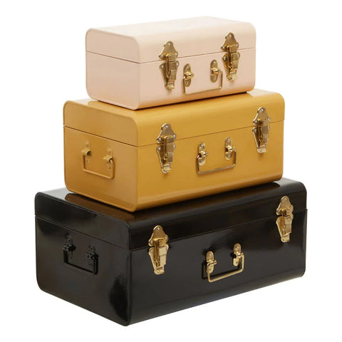 Set of three metal storage trunks in cream, mustard, and black with gold clasps and handles