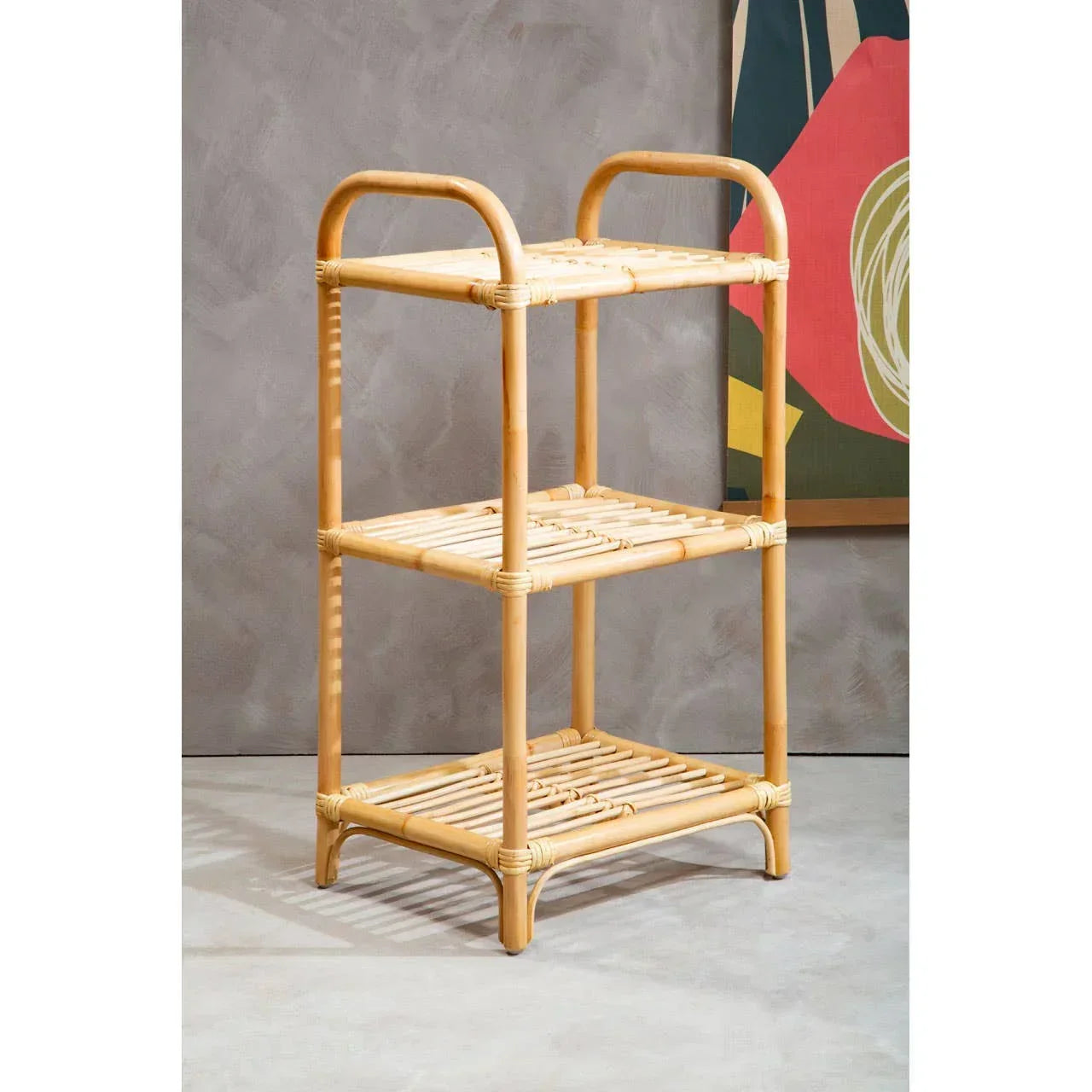 Three tier rattan shelving unit with natural bamboo finish against a grey wall