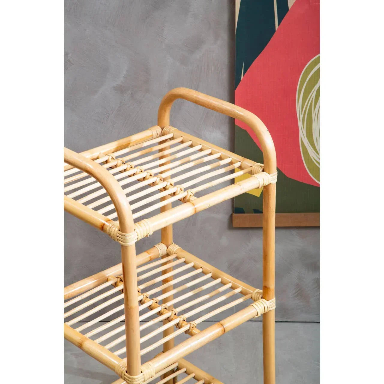 Natural rattan storage shelf with three slatted tiers against a grey textured wall