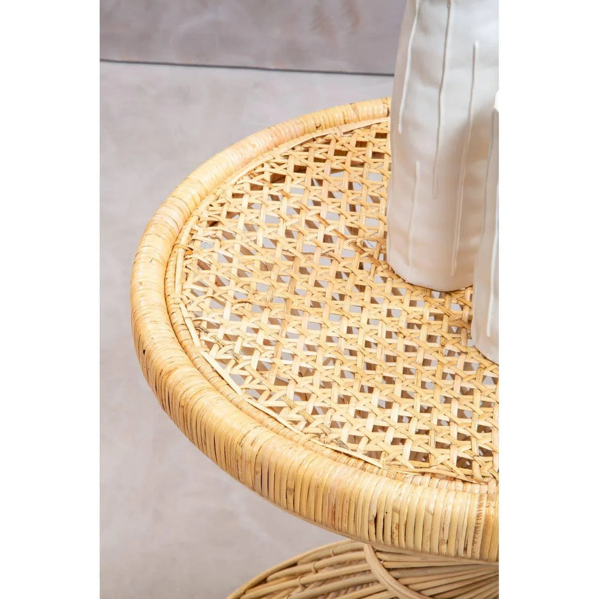 Round rattan side table with woven top and two white ceramic vases