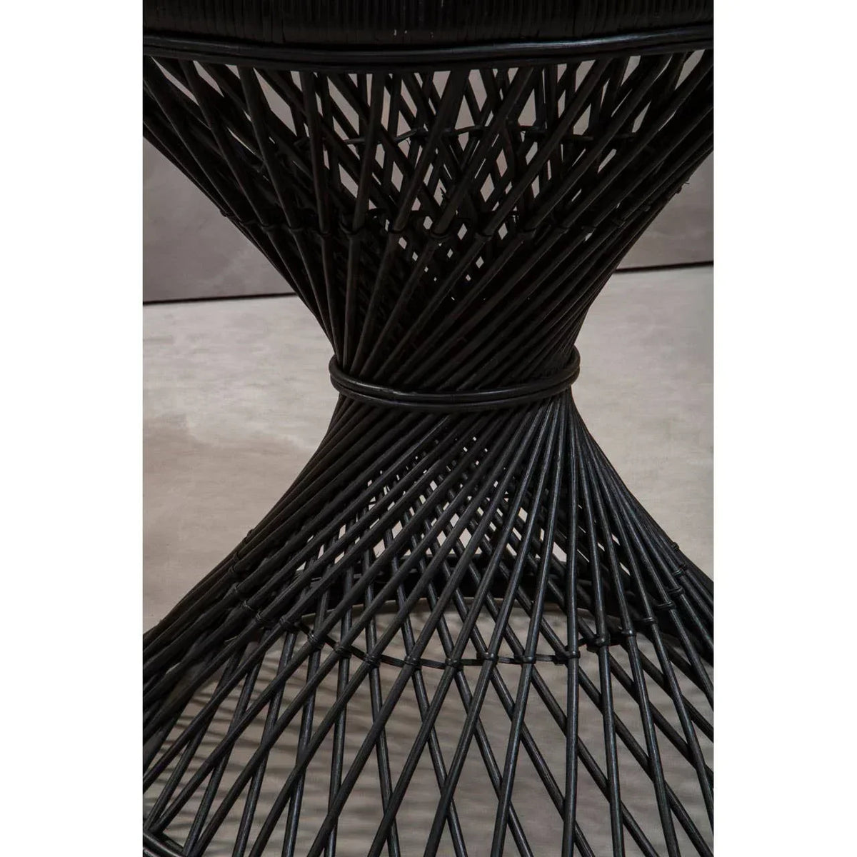 Black rattan dining table base with geometric crisscross pattern, close-up view