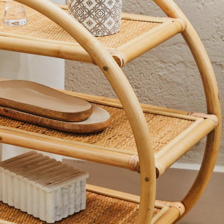 Three tier bamboo shelving unit with woven rattan shelves and decorative items