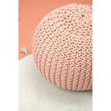 Round pink pouffe with a textured knit design, placed on a light surface with a soft peach background. The pouffe features a cozy, inviting appearance, suitable for children's rooms or play areas