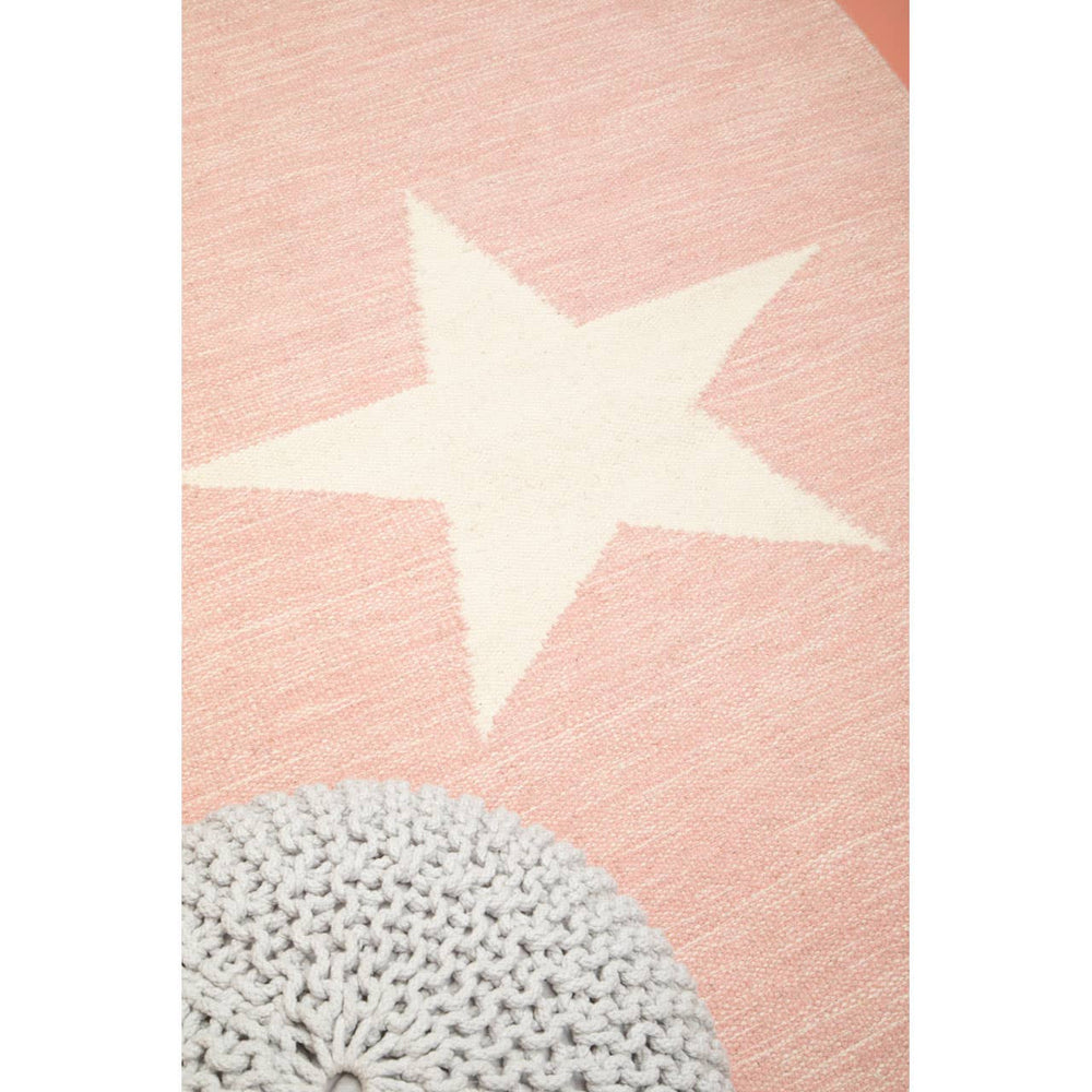 A soft grey knit pouffe designed for kids, featuring a textured surface and a cozy appearance, placed on a light pink rug with a large cream star and a circular grey pattern