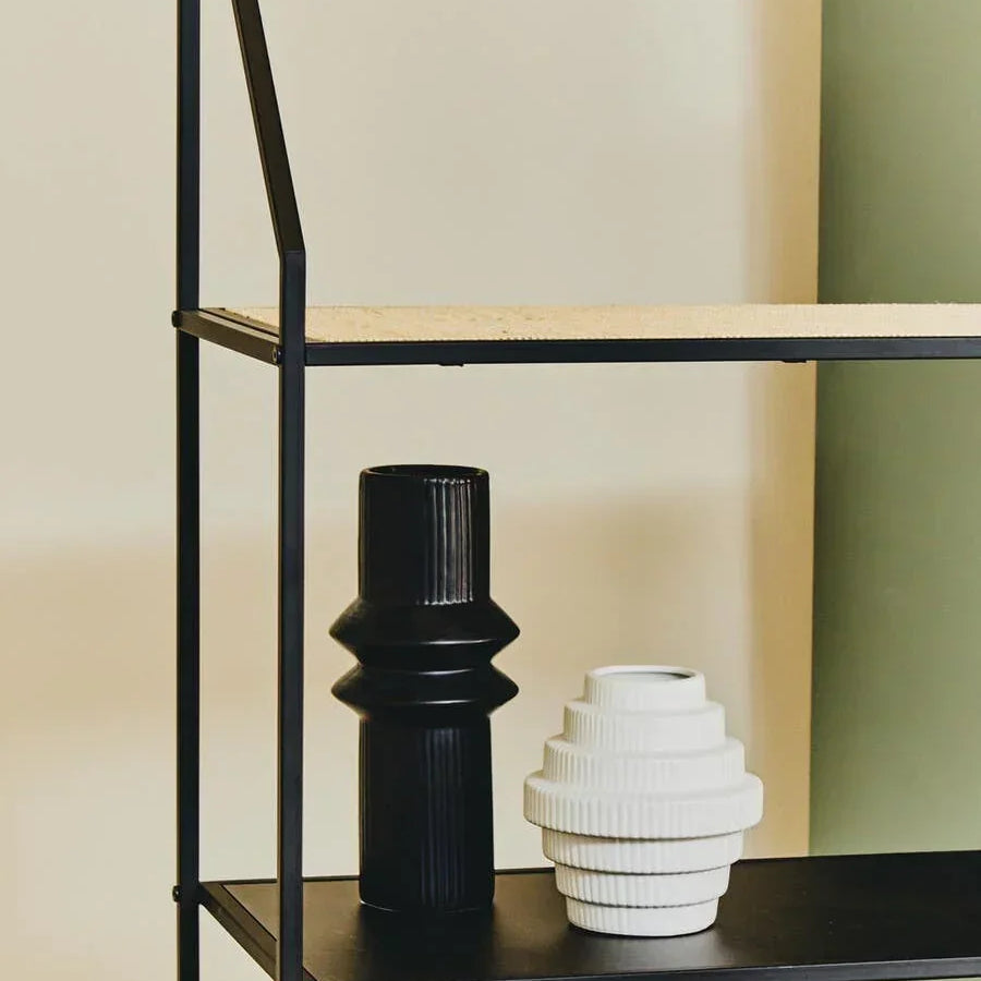 Black and white ceramic vases on modern black metal shelving unit against cream wall