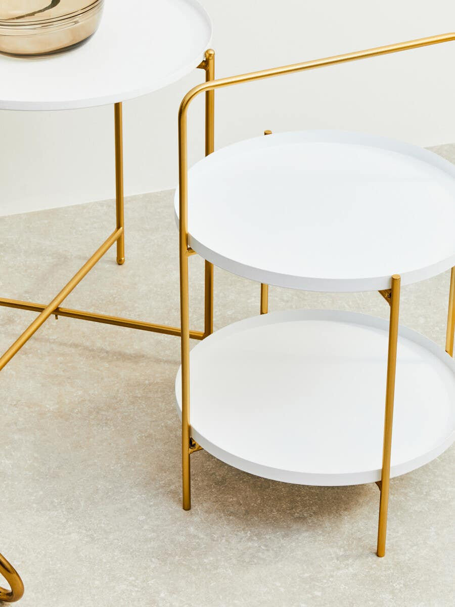 Two-tier side table featuring a sleek white finish on the circular surfaces and a stylish gold metal frame. The table has a modern design with slender legs and a minimalist aesthetic, suitable for various home decor styles