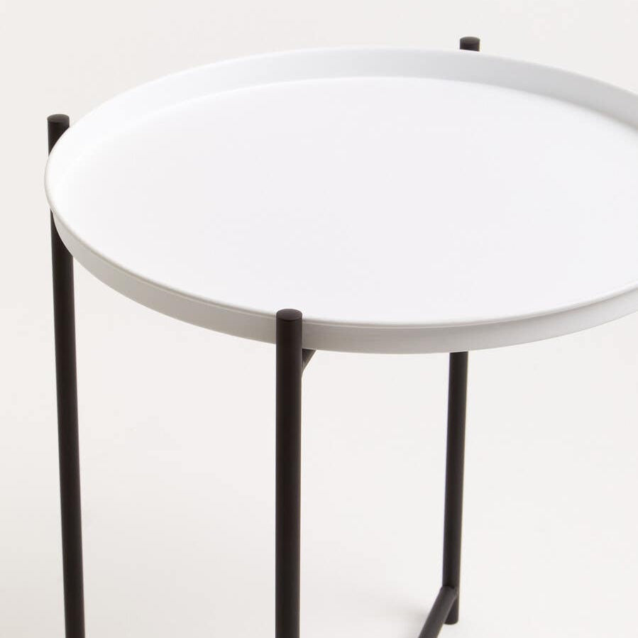 Round white tabletop supported by a sleek black metal frame, featuring four slender legs. The design is modern and minimalistic, suitable for various home decor styles