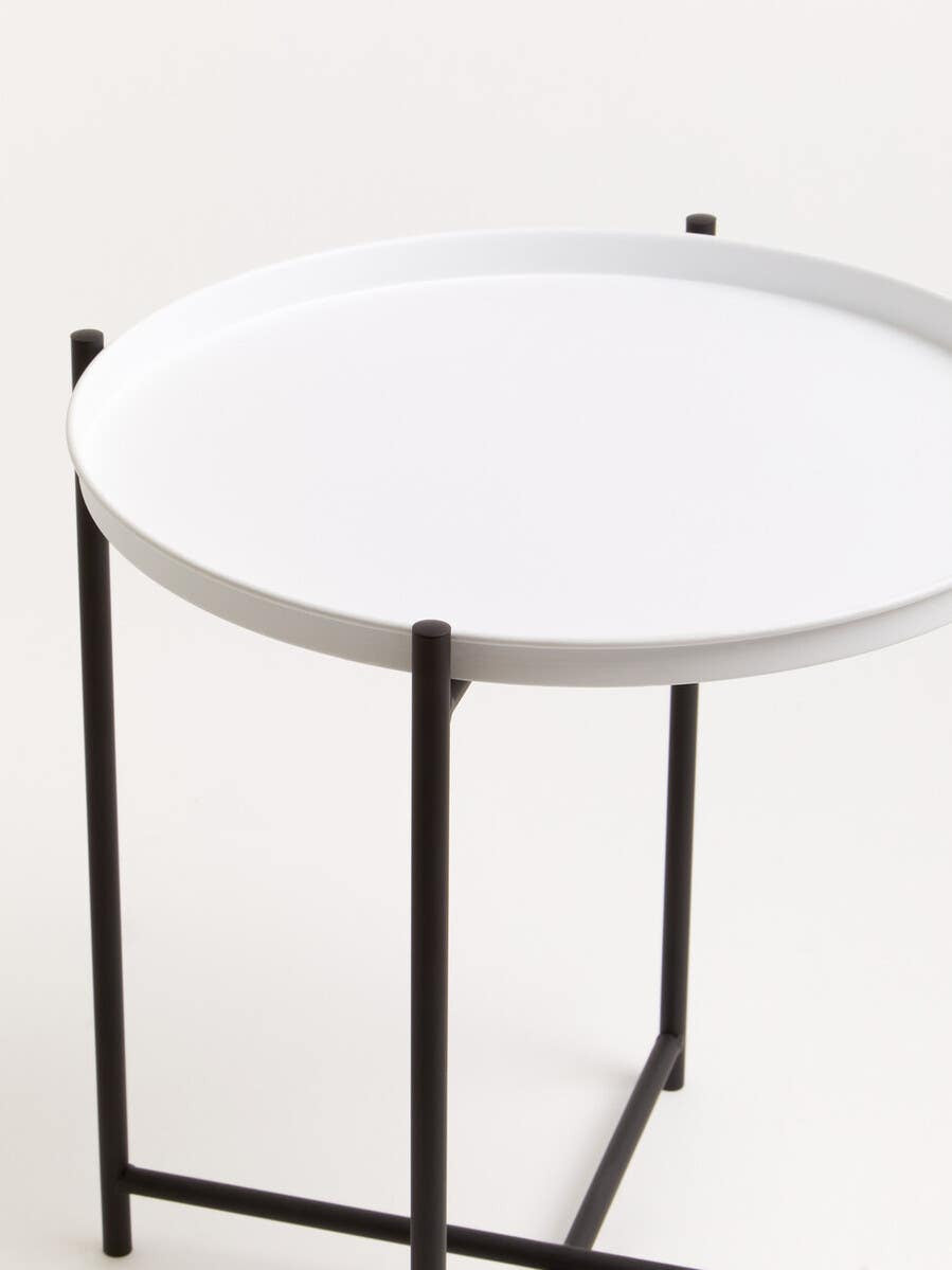 Round white tabletop supported by a sleek black metal frame, featuring four slender legs. The design is modern and minimalistic, suitable for various home decor styles