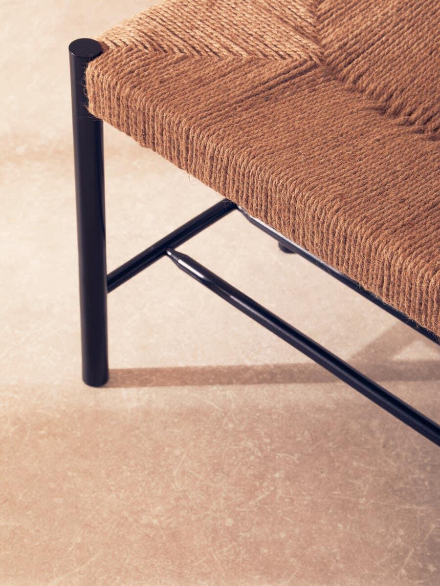 Woven rope seat with black metal frame, close-up of contemporary dining chair corner