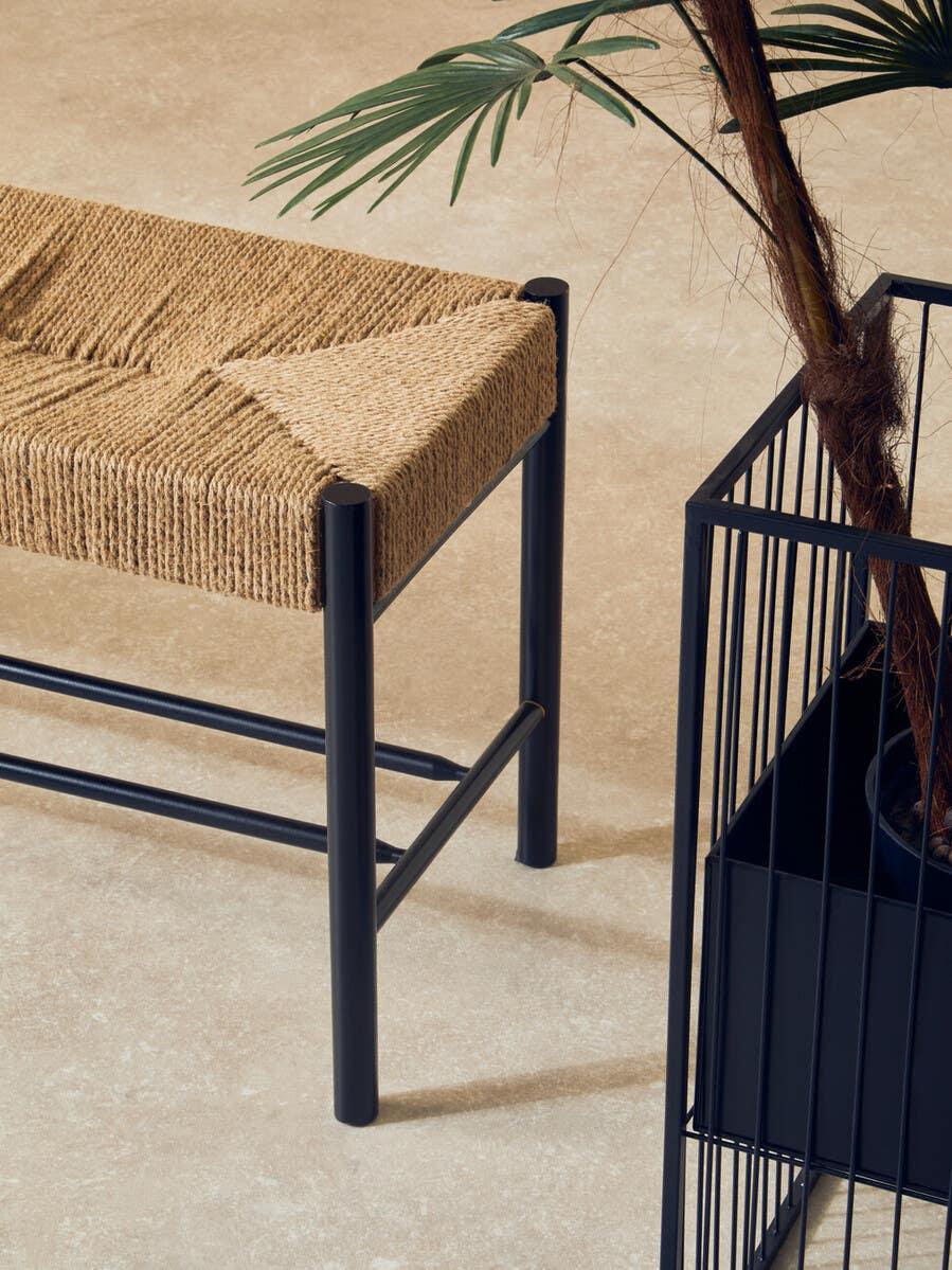 Jute rope bench with black metal frame beside potted plant in black wire planter