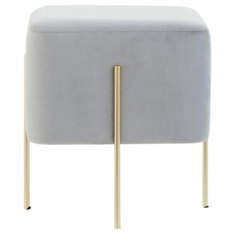 Square stool upholstered in soft grey velvet with four slender gold metal legs. The design features a minimalist aesthetic, suitable for modern home decor