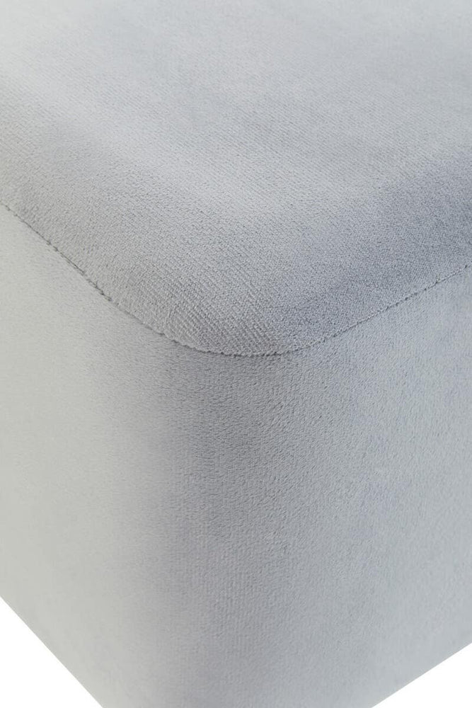 Square stool upholstered in soft grey velvet, featuring clean lines and a smooth surface. The edges are slightly rounded, and the fabric has a subtle sheen, adding a touch of elegance