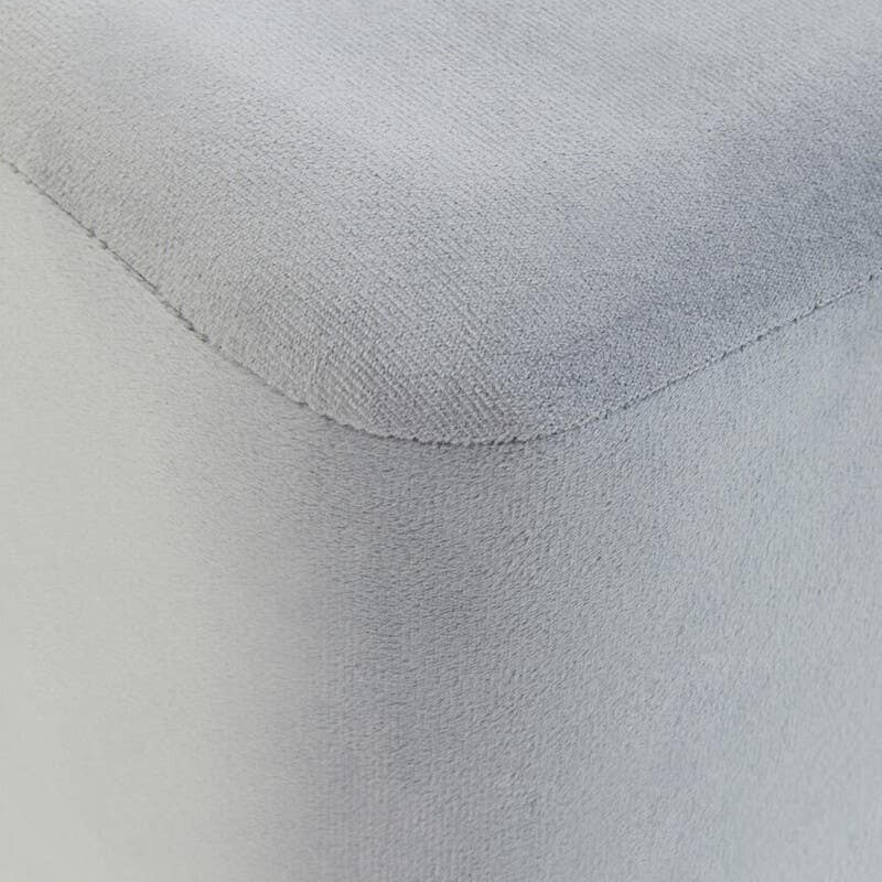 Square stool upholstered in soft grey velvet, featuring clean lines and a smooth surface. The edges are slightly rounded, and the fabric has a subtle sheen, adding a touch of elegance