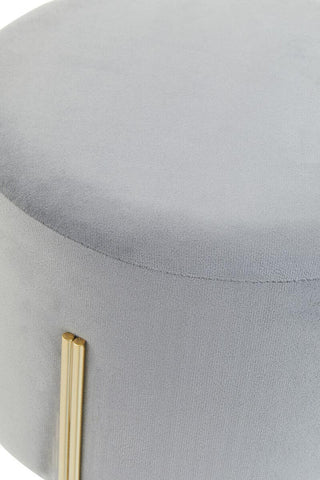 Round grey velvet stool with a smooth top surface and gold metal legs, showcasing a modern and elegant design