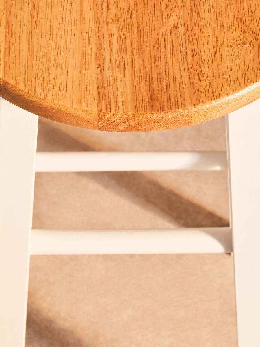 Round oak wood stool seat with white painted legs and crossbars, top angle view