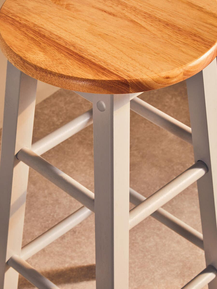Natural wood seat with a smooth finish, supported by a grey wooden frame featuring a cross-brace design for stability. The stool is set against a neutral background, highlighting its modern and rustic aesthetic