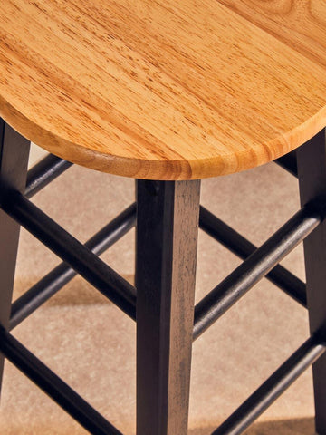 close-up of wooden bar stool seat with black legs and crossbar supports