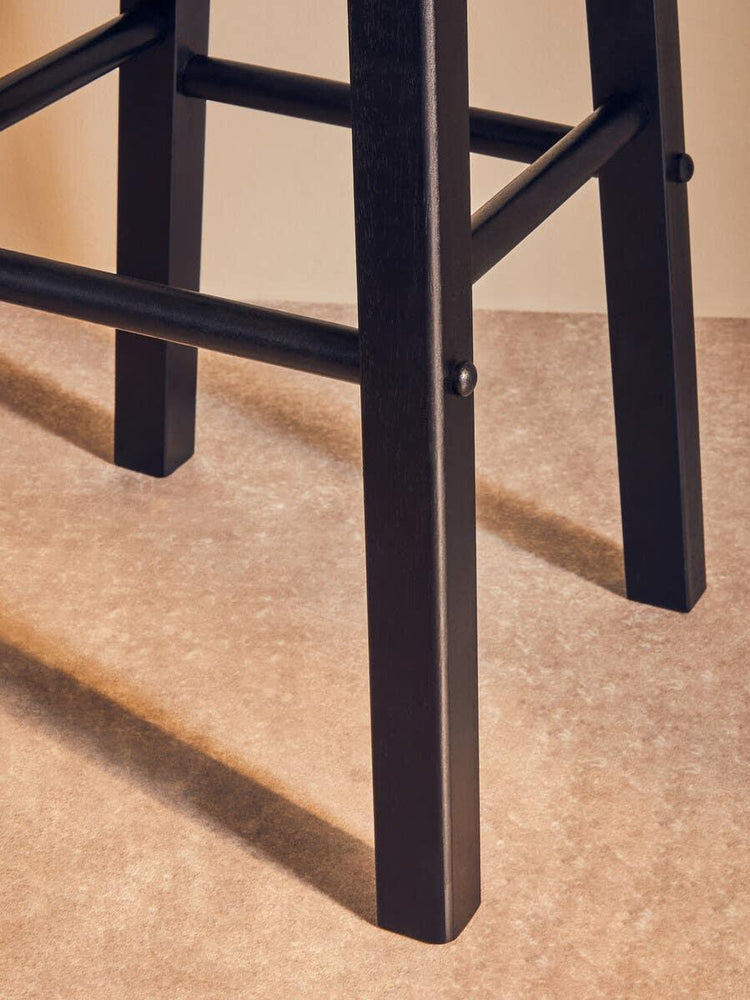 Black wooden chair legs with cross supports on neutral flooring